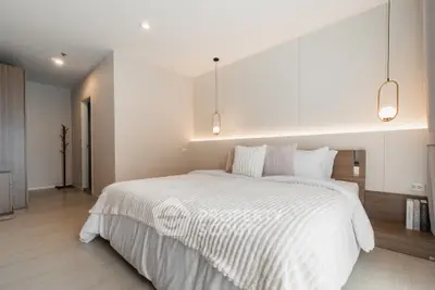 Luxurious modern bedroom with elegant lighting and cozy bedding in a stylish apartment.