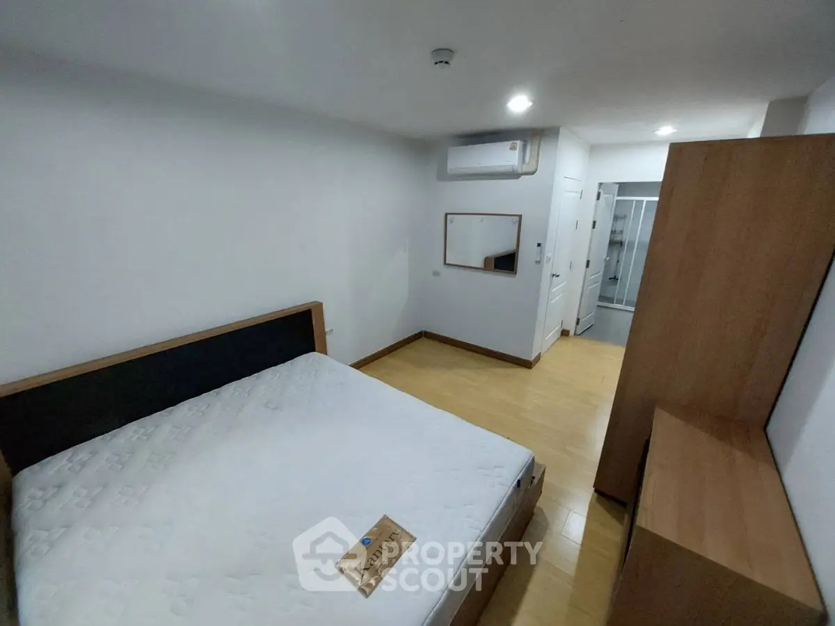 Spacious bedroom with modern furnishings and ample storage in a well-lit apartment.