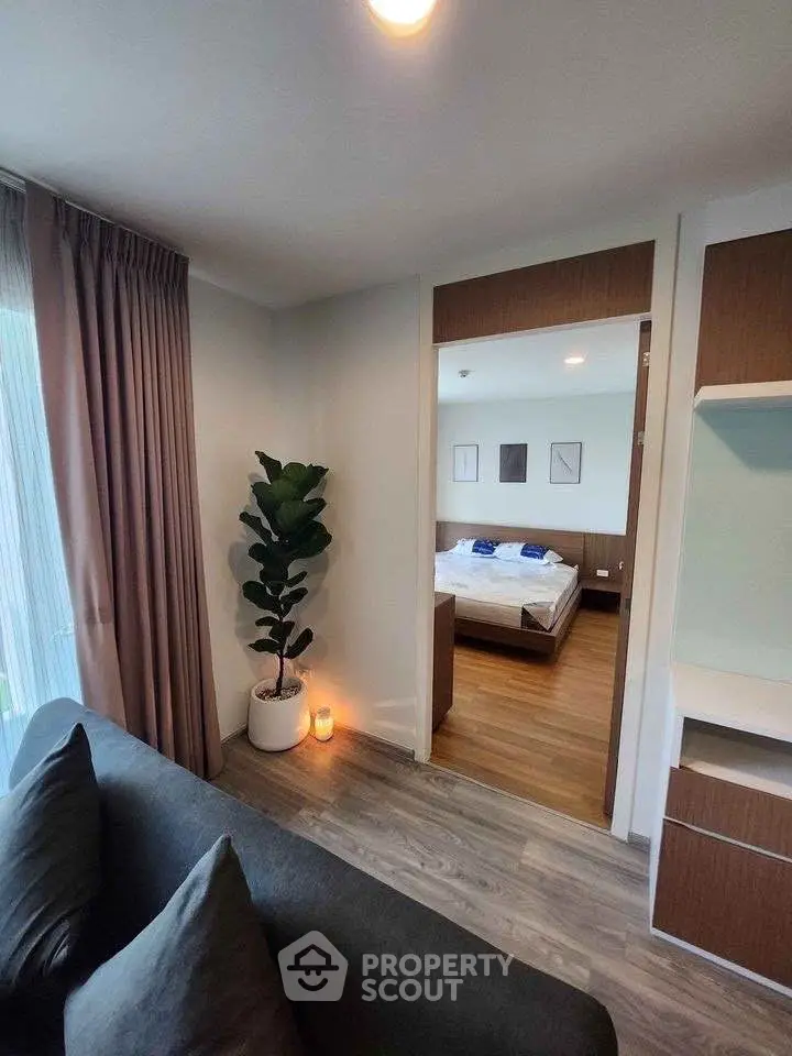 Modern apartment interior with cozy living room and view into stylish bedroom.