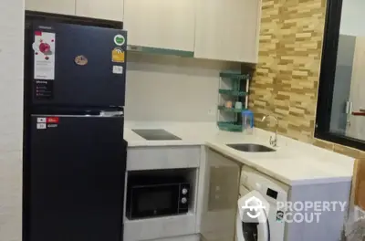 Modern kitchen with appliances including fridge, microwave, and washing machine in compact layout.