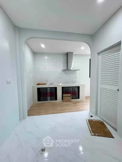 Modern kitchen with sleek design and open layout, featuring white cabinetry and stainless steel appliances.