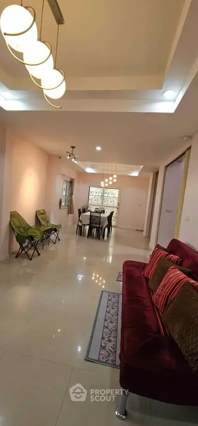 Spacious living room with modern lighting and elegant furniture, perfect for family gatherings.