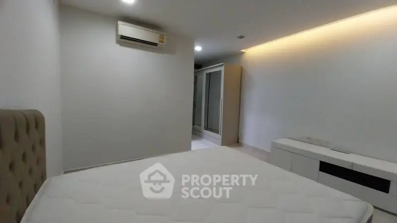 Modern minimalist bedroom with air conditioning and sleek storage solutions.