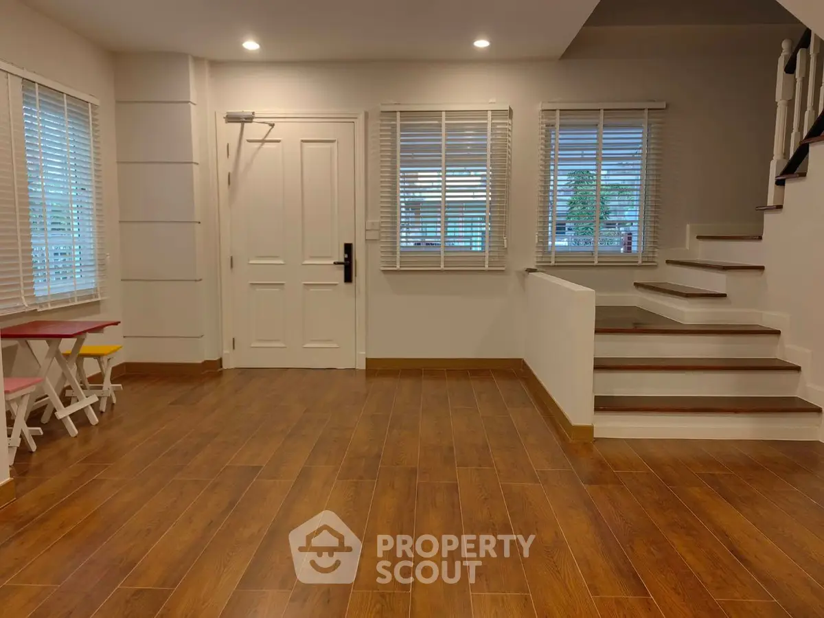 Spacious living room with wooden flooring and natural light, perfect for family gatherings.