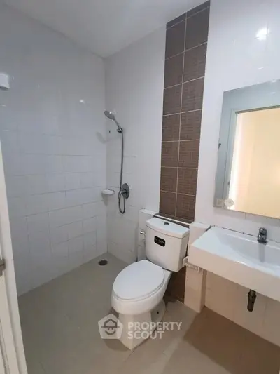 Modern bathroom with sleek fixtures and tiled walls, featuring a shower and a contemporary sink.