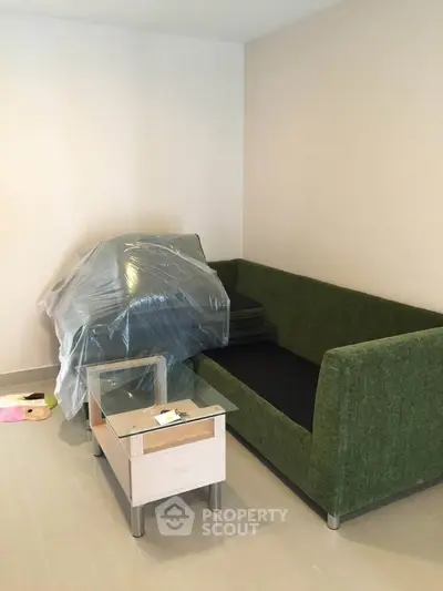 Modern living room with green sofa and glass coffee table in a cozy apartment.