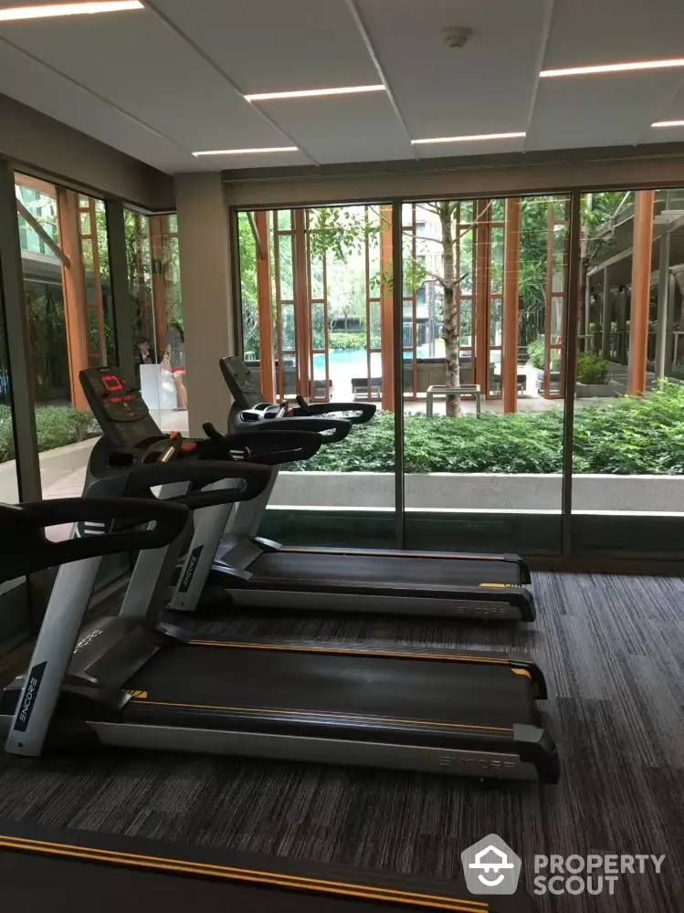 Modern gym with treadmills and garden view in luxury residential complex