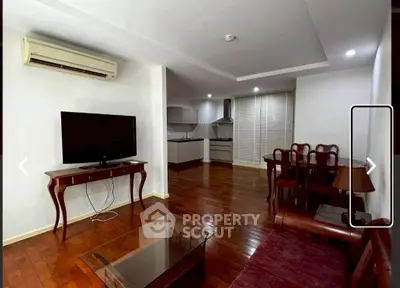 Spacious living room with elegant wooden flooring and modern kitchen in open layout