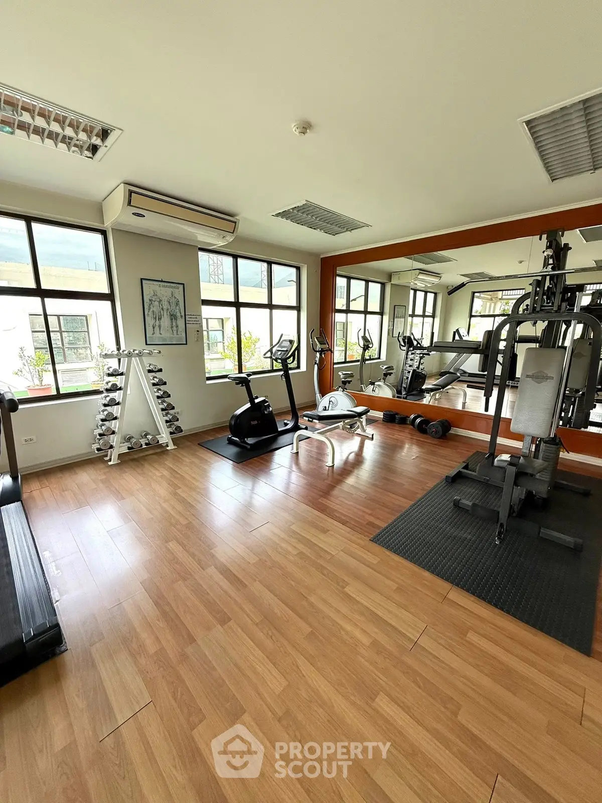 Spacious gym with modern equipment and large windows in a residential building.