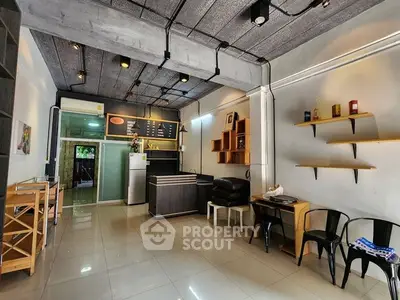 Modern open-layout living space with industrial ceiling and sleek furnishings.