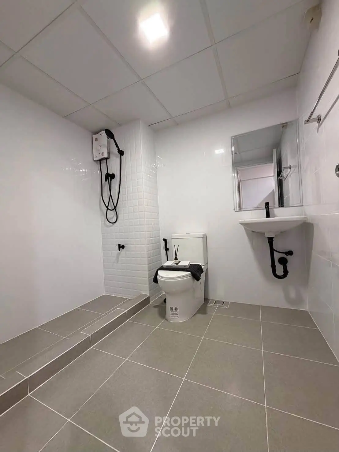 Modern bathroom with sleek design, featuring a shower, toilet, and minimalist fixtures.