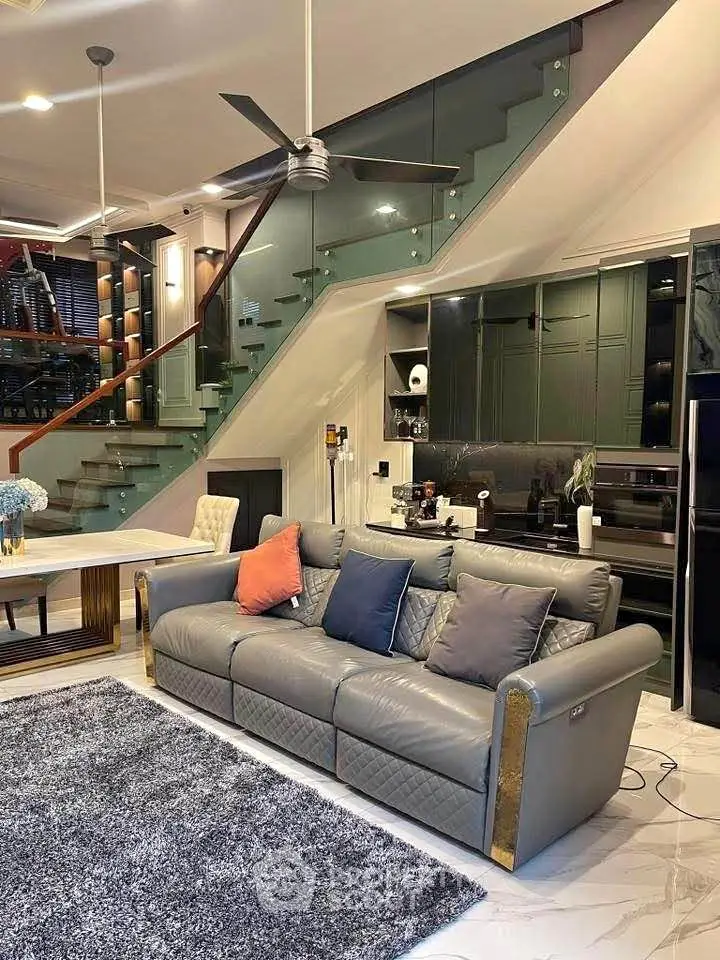 Luxurious modern living room with stylish sofa, elegant staircase, and sleek kitchen design.