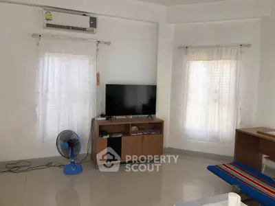 Spacious living room with modern TV setup and air conditioning, perfect for relaxation.