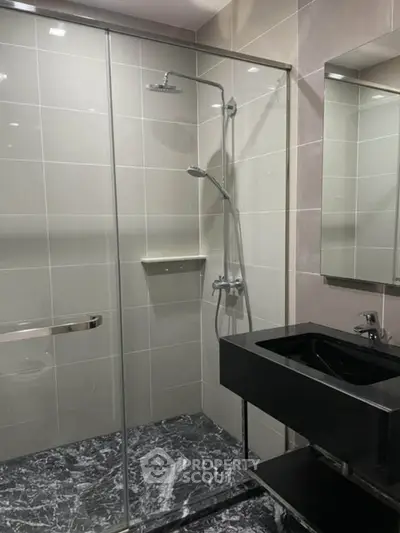 Modern bathroom with sleek black sink and glass shower enclosure
