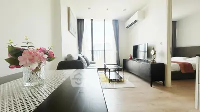 Modern living room with stylish decor and natural light, featuring a cozy seating area and sleek entertainment unit.
