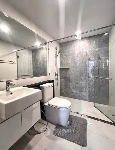 Modern bathroom with sleek design, featuring a glass-enclosed shower and contemporary fixtures.