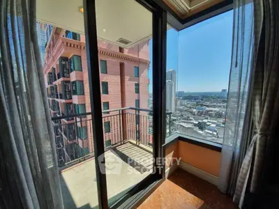 Stunning city view from a high-rise apartment balcony with glass doors.