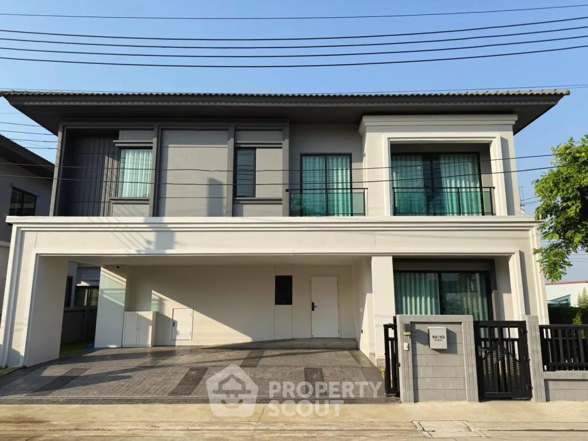 Modern two-story house with sleek design and spacious driveway in a suburban neighborhood.