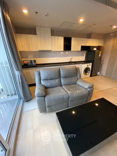Modern kitchen with sleek cabinets, washing machine, and cozy seating area