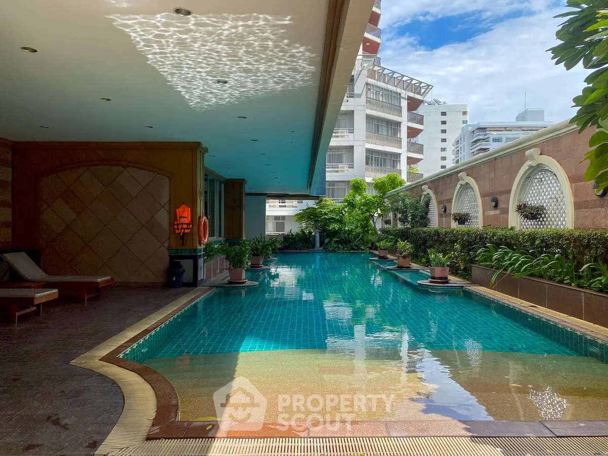 Luxurious outdoor pool area with lush greenery and city views, perfect for relaxation and leisure.