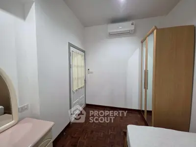 Cozy bedroom with air conditioning and wooden flooring, featuring a wardrobe and vanity for ample storage.