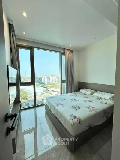 Modern bedroom with large windows offering stunning city views and elegant decor.