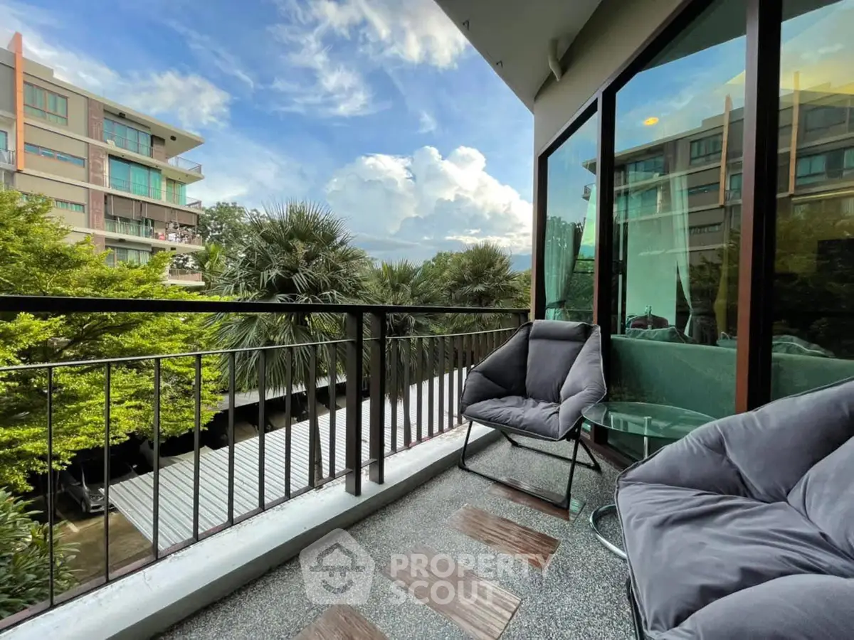 Charming balcony with cozy seating and lush views in modern apartment complex.