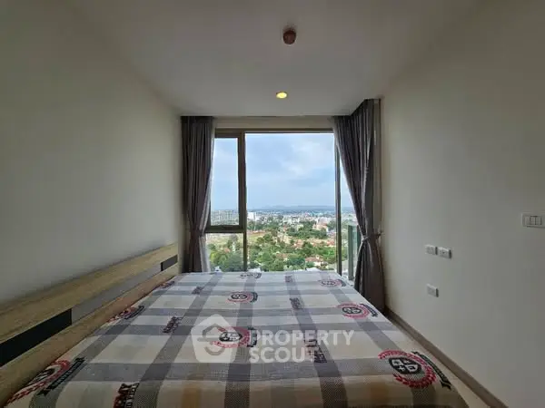 Spacious bedroom with stunning city view and large window, perfect for relaxation and comfort.