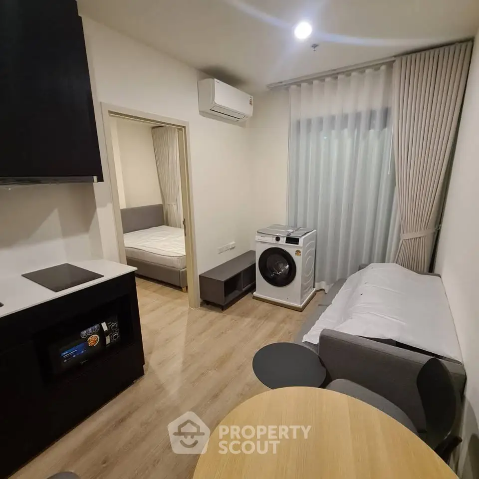 Modern studio apartment with open layout, featuring a cozy living area, compact kitchen, and in-unit washing machine.