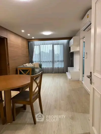 Spacious living room with modern decor and large window, perfect for relaxation and entertaining.