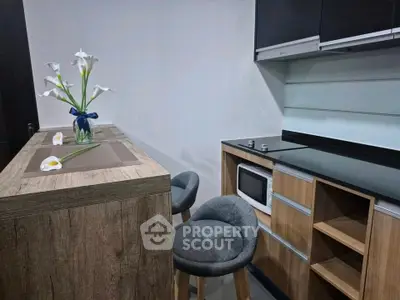 Modern kitchen with sleek black countertops and stylish wooden cabinetry, featuring a cozy breakfast bar and elegant decor.
