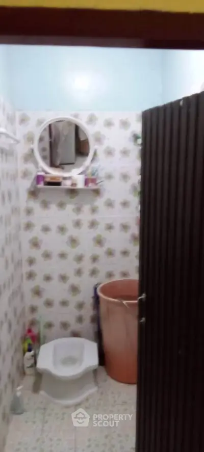 Compact bathroom with floral tiles and essential amenities.
