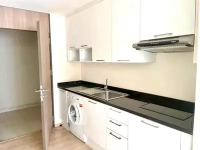 Modern kitchen with sleek cabinets and built-in appliances, featuring a washing machine and electric stove.