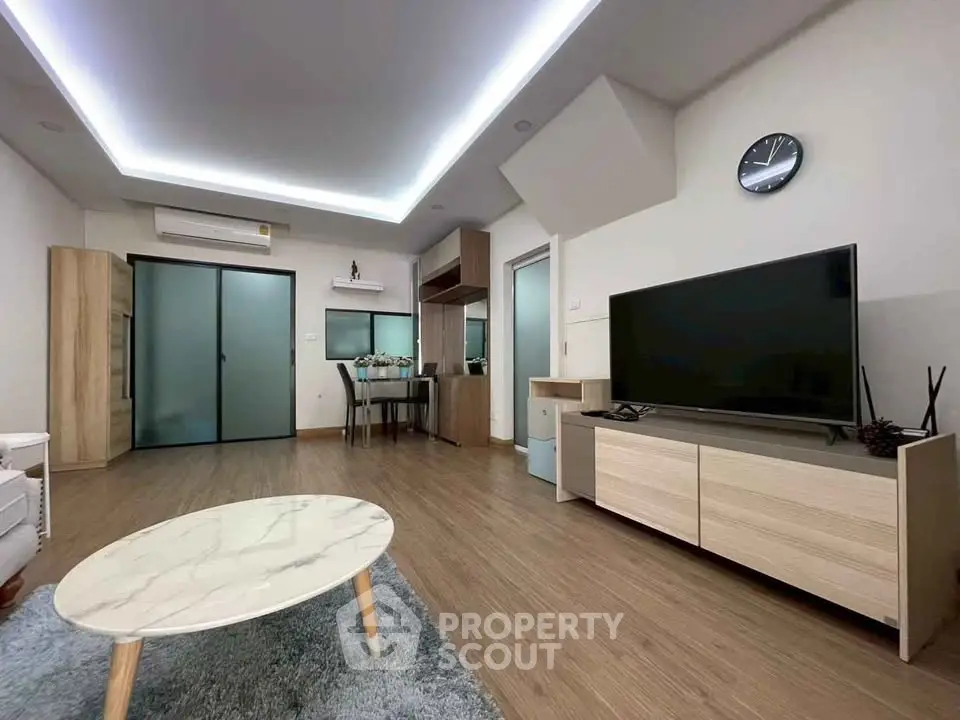 Modern living room with sleek design, featuring a marble coffee table, large TV, and stylish lighting.