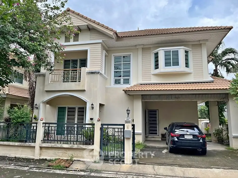 Charming two-story house with a carport and lush greenery, perfect for family living.