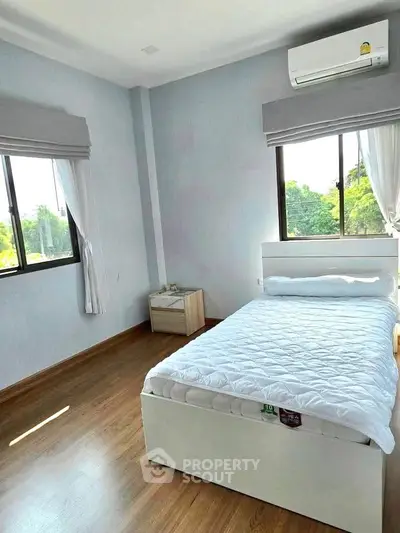 Bright and airy bedroom with large windows and modern air conditioning unit.