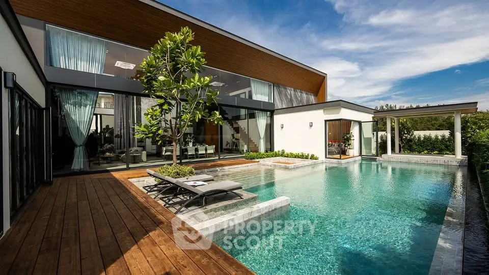 Luxurious modern villa with stunning pool and wooden deck, perfect for relaxation and entertainment.