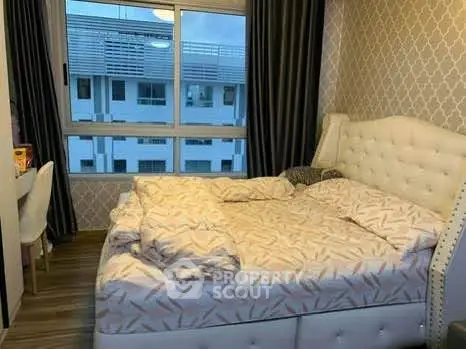 Cozy bedroom with elegant decor and large window offering natural light and city view.