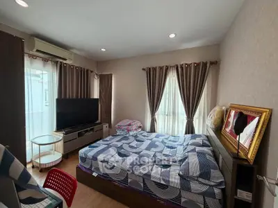 Spacious bedroom with modern decor and large windows for natural light.