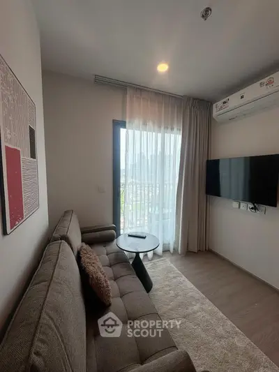 Modern living room with cozy sofa, wall-mounted TV, and balcony view in stylish apartment.