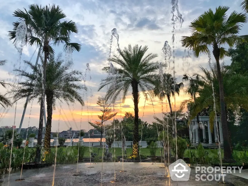 Stunning garden view with palm trees and water fountain at sunset