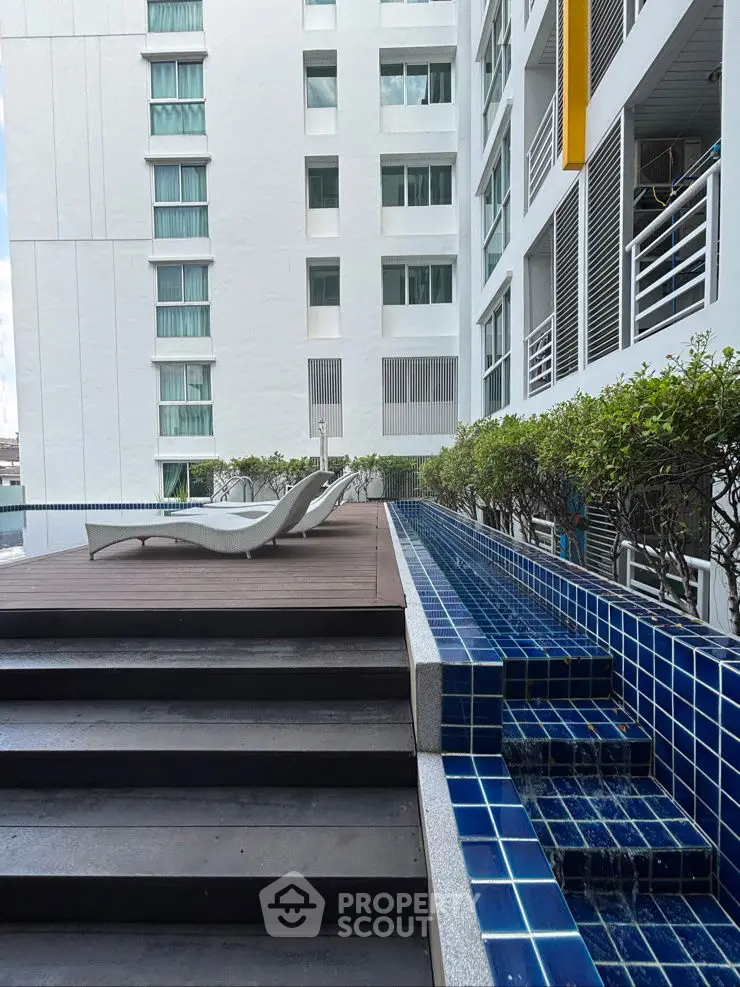 Modern apartment building with poolside deck and lounge chairs