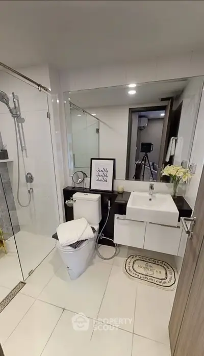 Modern bathroom with glass shower, sleek vanity, and elegant decor in a contemporary home.