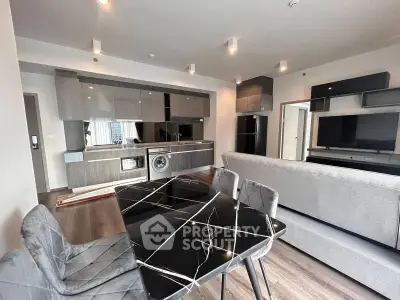 Modern open-plan living room with sleek kitchen and stylish dining area in contemporary apartment.