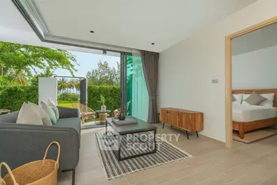Modern living room with open balcony and garden view, featuring stylish furniture and natural light.
