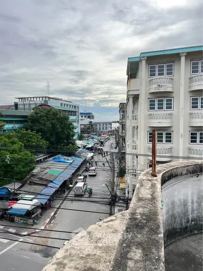 Urban street view with residential buildings and bustling market below, showcasing vibrant city life.