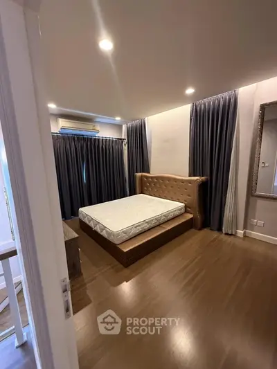 Spacious bedroom with elegant decor and large windows for natural light.