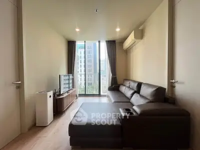 Modern living room with sleek furniture and city view through large windows.