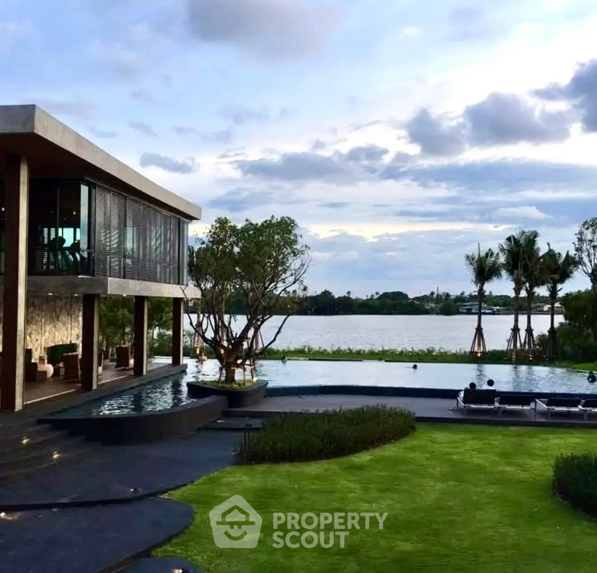 Luxurious modern villa with stunning lake view and infinity pool, surrounded by lush greenery.