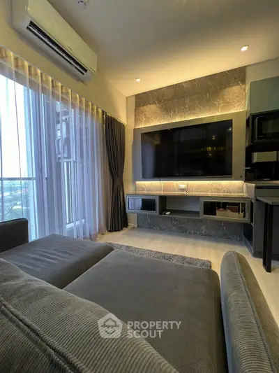 Modern living room with sleek entertainment center and large sofa, featuring ambient lighting and floor-to-ceiling windows.